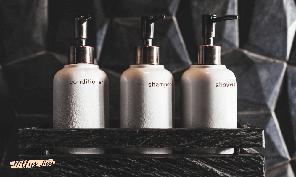 Tre elegante dispenserflasker med balsam, shampoo og shower gel på række.