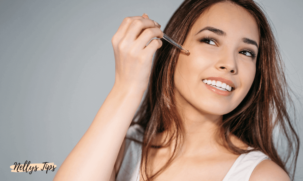 Kvinde smører skin tint eller dagkräm i ansigtet med fingrarne for jämn hudton